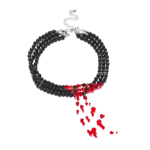 Detail view of multi-layered black beaded necklace with red blood drop tassel and lobster clasp