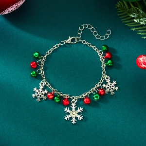 Detail of Christmas bracelet with silver snowflake charms and red green bells on green background