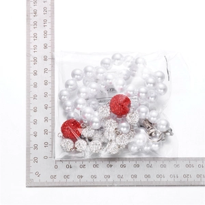 Detail of beaded trousers chain with white pearls and red rhinestone balls in 10-15cm length