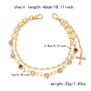 Detail of gold pants chain with colorful hearts, pearls, cross pendant and lobster clasp