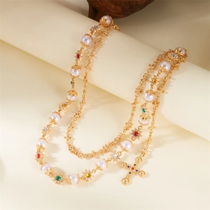 Detail of double-layer gold necklace with pearls, colored gems and a large cross pendant