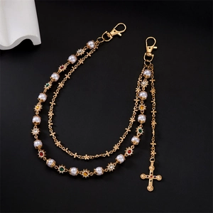 Detail of gold multilayer trouser chain with pearls, rhinestones and cross pendant