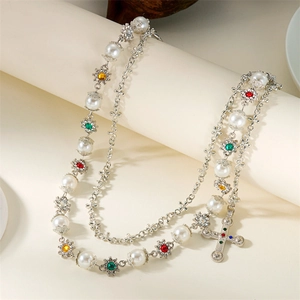 Detail of layered necklace with colorful gemstones, white pearls and a cross pendant