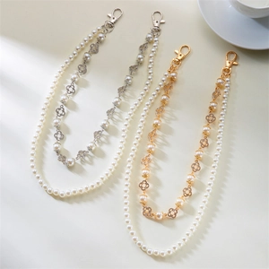 Detailed view of pearl chain straps with diamond-encrusted clover and lobster clasps