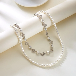 Detail of layered pearl chain featuring a sparkling rhinestone four-leaf clover pendant