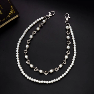 Detail of double-layer chain with white pearls and silver hollow clover charms on black base