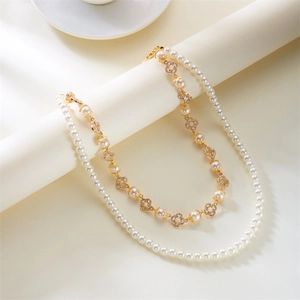 Detail of double-layer pearl necklace with golden clover pendants and crystal inlay
