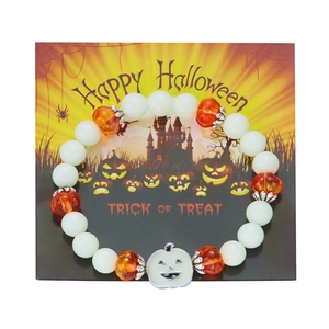 Close-up of Halloween beaded bracelet with glowing pumpkin charm on festive card