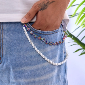 Detail of hip-hop layered trouser chain with pearls and colorful rhinestone balls on denim