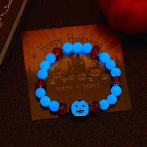 Glow-in-the-dark Halloween bracelet with blue luminous beads and pumpkin charm in darkness