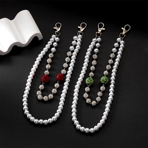 Detailed macro view of pearl hip-hop chain with red and green rhinestone balls and gold clasp