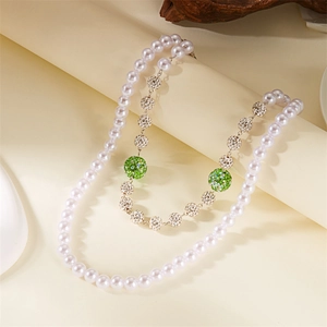 Detail of double-layer necklace with white faux pearls and green rhinestone balls