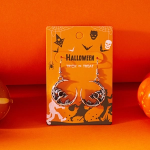 Detail of Gothic silver skull and crescent moon earrings on a festive orange Halloween card