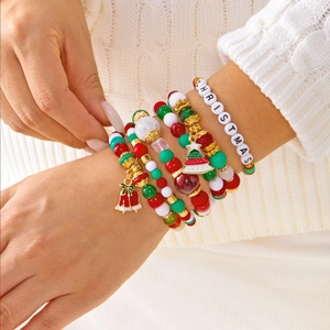 Gros plan de bracelets de Noël avec flocons de neige et cloches sur un pull en tricot