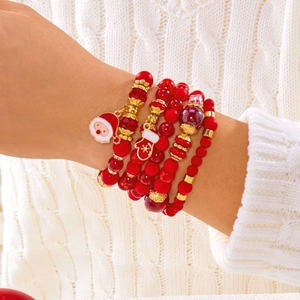 Détail de bracelets de Noël en perles rouges avec breloques Père Noël portés au poignet