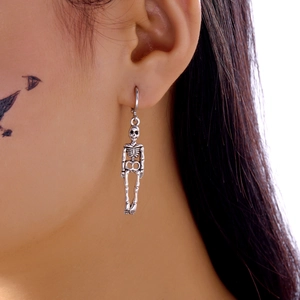 Detail view of gothic silver skeleton drop earrings worn on ear for Halloween party