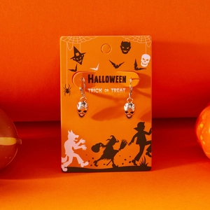 Detail of silver skull earrings with vintage texture on a festive Halloween display card