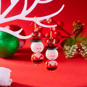 Gros plan de boucles d'oreilles Père Noël en perles de bois sur branche blanche
