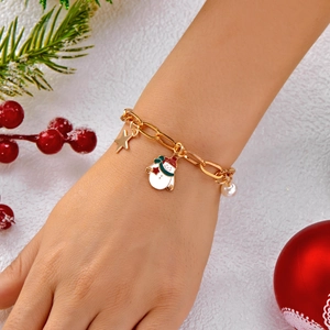 Dettaglio del bracciale natalizio dorato con ciondoli pupazzo di neve, stella e perla su sfondo a tema