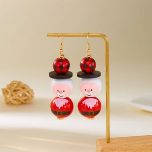 Détail des boucles d'oreilles en perles de bois Père Noël sur un support doré