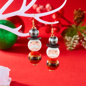 Détail de boucles d'oreilles festives en perles de bois avec motifs Père Noël et casse-noisette
