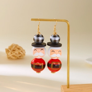 Gros plan de boucles d'oreilles Père Noël en perles de bois suspendues sur support doré