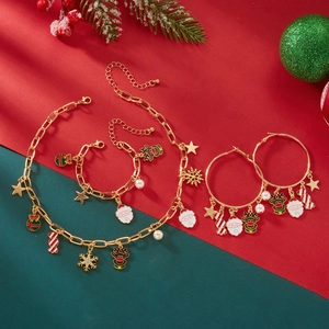 Set gioielli natalizi con collana e bracciale dorati e ciondoli festivi su sfondo rosso