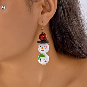 Gros plan de boucles d'oreilles bonhomme de neige en perles de bois portées par un modèle
