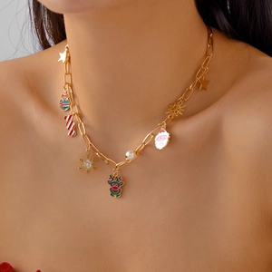 Dettaglio di una collana natalizia dorata con ciondoli festivi e perla bianca su modella