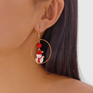 Model wearing gold Christmas snowman earrings with red beads and enamel finish