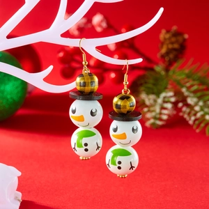 Détail de boucles d'oreilles bonhomme de neige en bois avec écharpe verte sur branche