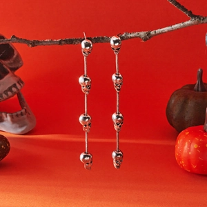 Halloween silver tassel earrings with four stacked skulls on a snake chain pendant