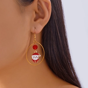 Close-up of a gold festive hoop earring with a cute Santa Claus enamel charm and red bead