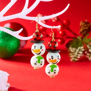 Détail de boucles d'oreilles bonhomme de neige avec perles en bois sur décor festif