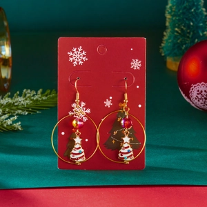 Detailed shot of Christmas tree drop earrings with colorful enamel on a festive red card