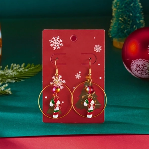Macro detail of Christmas candy cane earrings with red beads on a festive card