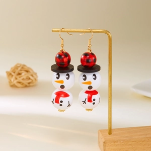 Détail de boucles d'oreilles bonhomme de neige en bois avec chapeau à carreaux rouges