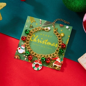 Dettaglio del bracciale natalizio con ciondoli di Babbo Natale e campanelli su carta festiva