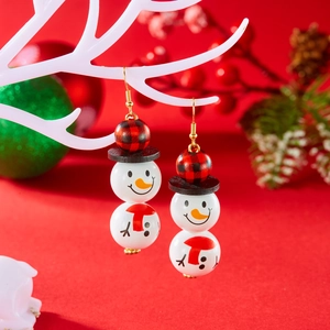 Détail de boucles d'oreilles bonhomme de neige en perles de bois sur branche de Noël