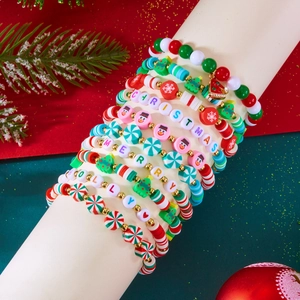 Close-up of handmade Christmas heishi bead bracelet set with snowman and tree charms
