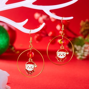 Close-up of Santa Claus enamel hoop earrings with red beads on a Christmas display