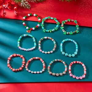 Macro shot of colorful Christmas beaded bracelets with Santa, tree, and holly clay charms
