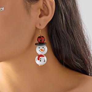 Gros plan de boucles d'oreilles bonhomme de neige en bois avec écharpe rouge