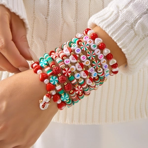 Close-up of layered Christmas bracelets with Santa, snowman charms and clay beads on wrist