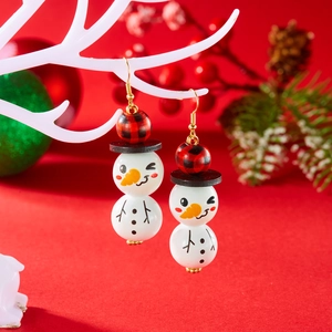 Détail de boucles d'oreilles bonhomme de neige festif avec perles à carreaux rouges