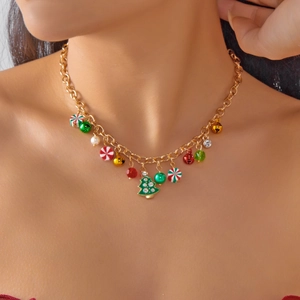 Dettaglio della collana dorata con albero di Natale, campanelli e perle su modella