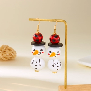 Détail de boucles d'oreilles bonhomme de neige avec perles à carreaux rouges sur socle