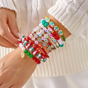 Close-up of multilayer Christmas beaded bracelets with festive charms and holiday text