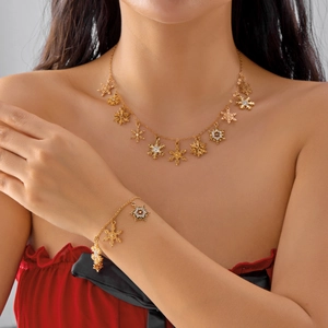 Model wearing gold snowflake necklace and bracelet set with sparkling crystals