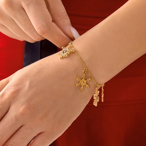 Detailed view of a gold-tone bracelet with sparkling snowflake charms on red fabric